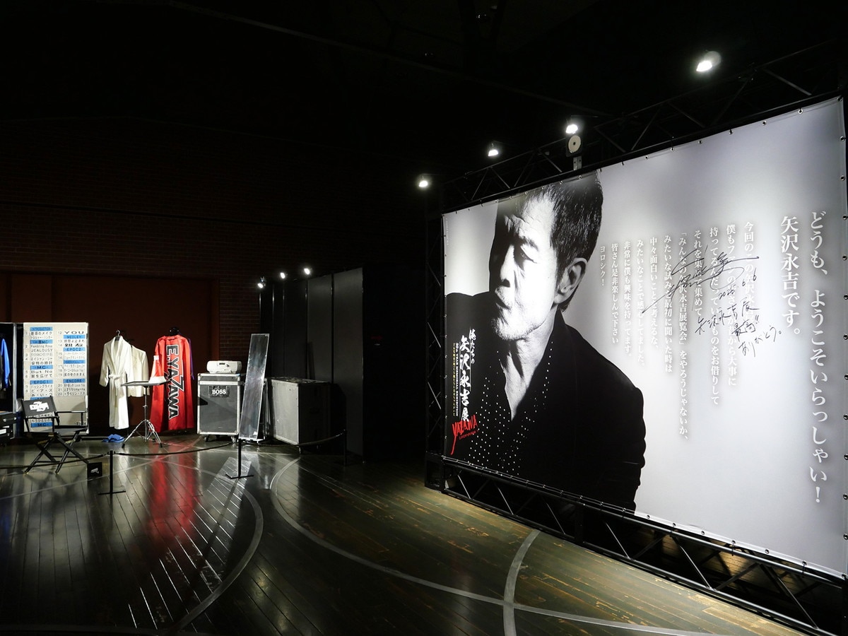 直筆サインが書かれているウェルカムボードと楽屋を再現した展示風景