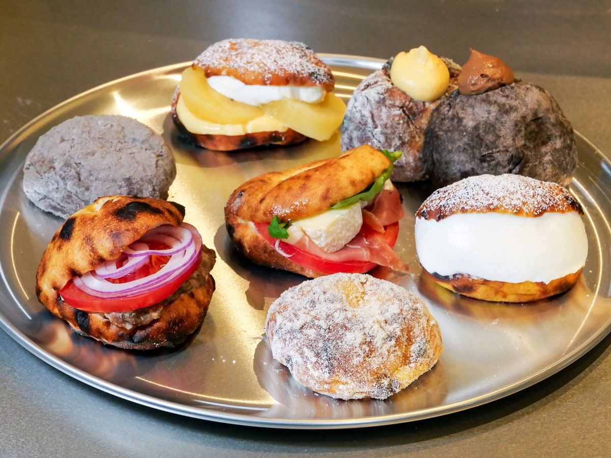 新商品や横浜臨港パーク店限定商品。手前から時計回りに、生ナポリドーナツ、ナポリバーガー、生ナポリドーナツカカオ、季節のフルーツサンド、生ナポリドーナツ（カスタード、チョコカスタード）、マリトッツォ、中央はナポリサンド