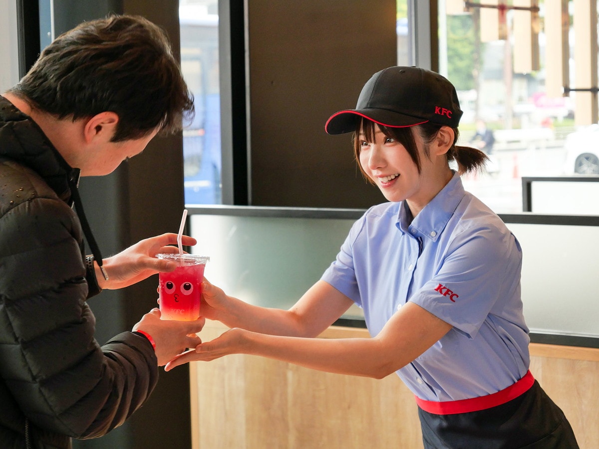 KFC店員（マネージャー）の制服に着替え、「ちゅる～りぃ」を手渡す、えなこさん