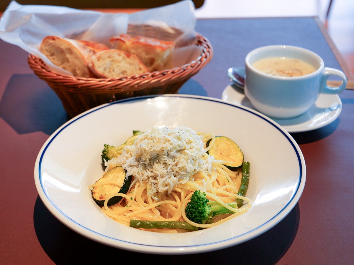 おかわり自由のパンが付くランチメニュー。画像は「たっぷりしらすと緑野菜のペペロンチーノ」（税込1870円）、セットスープ（税込330円）（筆者撮影）