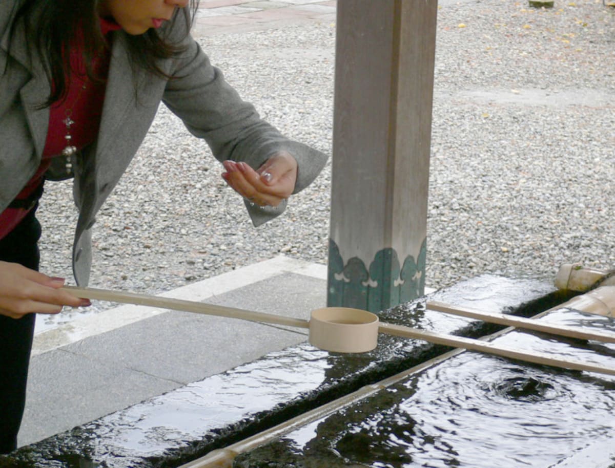 手水のやり方・手水舎での作法3：再び柄杓を右手に持ち替え、左の掌に水を受けて口をすすぐ