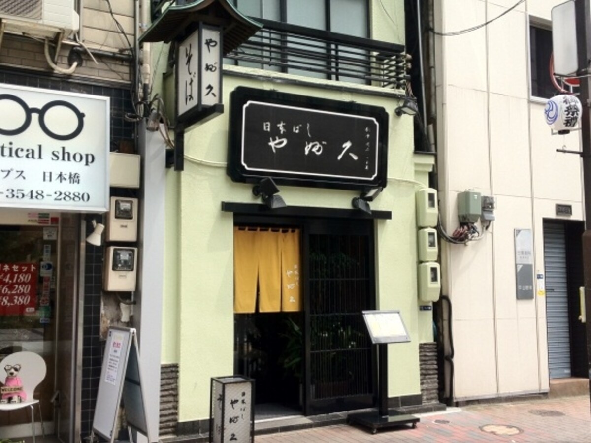 薄いうぐいす色の壁に黒の看板が印象的な同店
