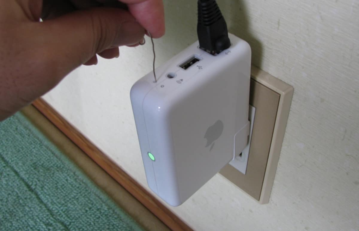 リセットボタンはクリップのようなもので軽く押さえて操作します。AirMac Expressの設定中はさかさまにしておくと便利です（設定が終わったら挿し直してください）