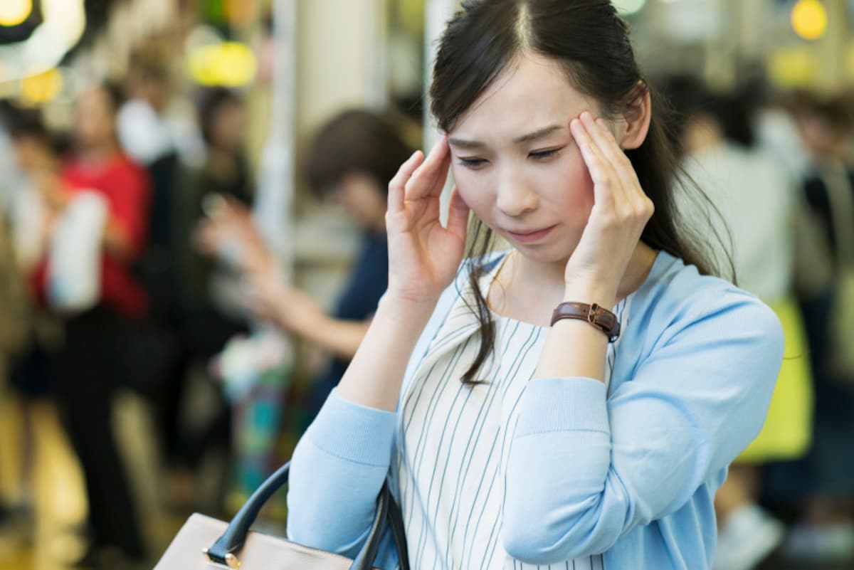 こめかみを押さえる女性