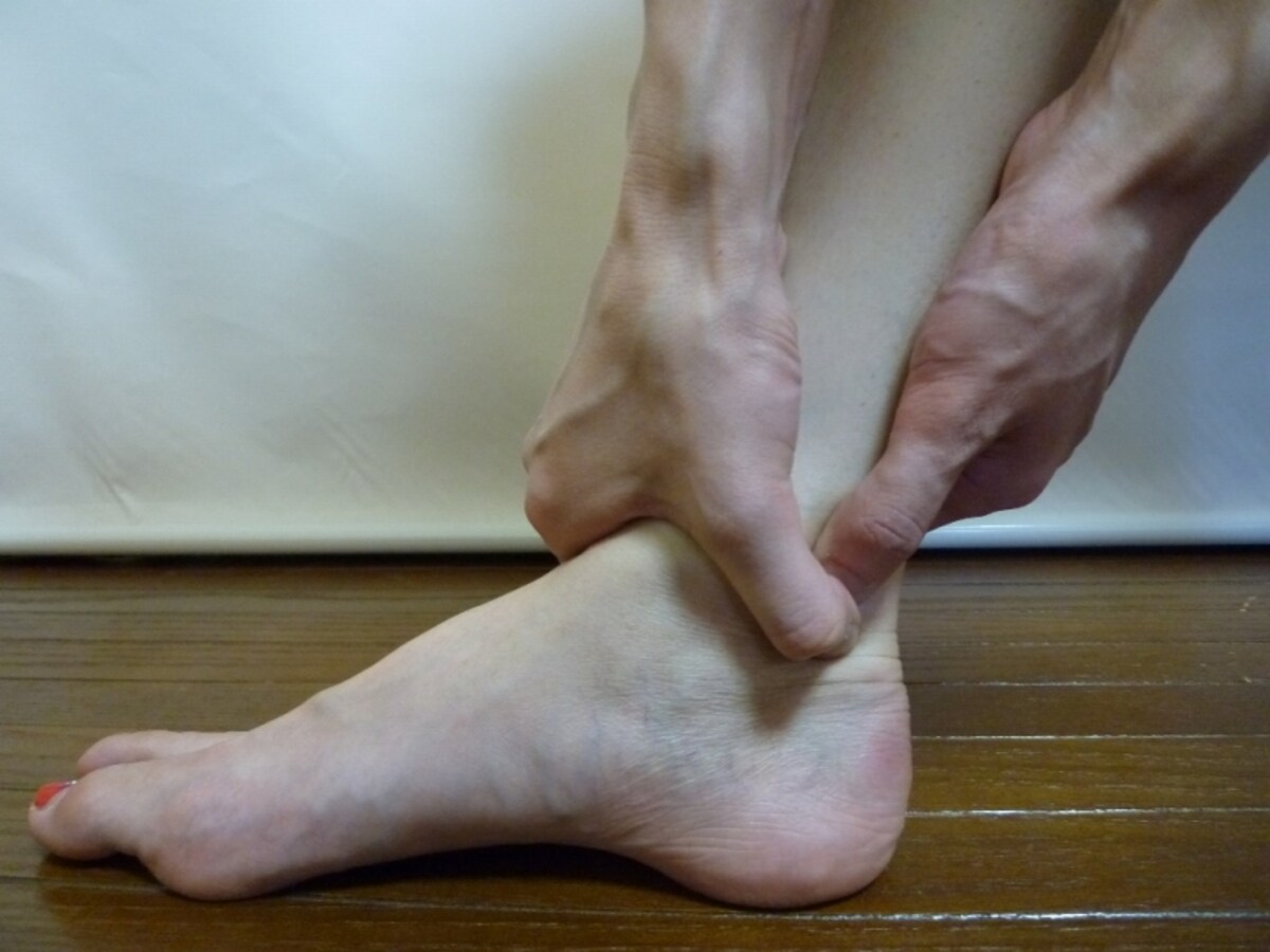 親指で押さえ両手で足首を握る