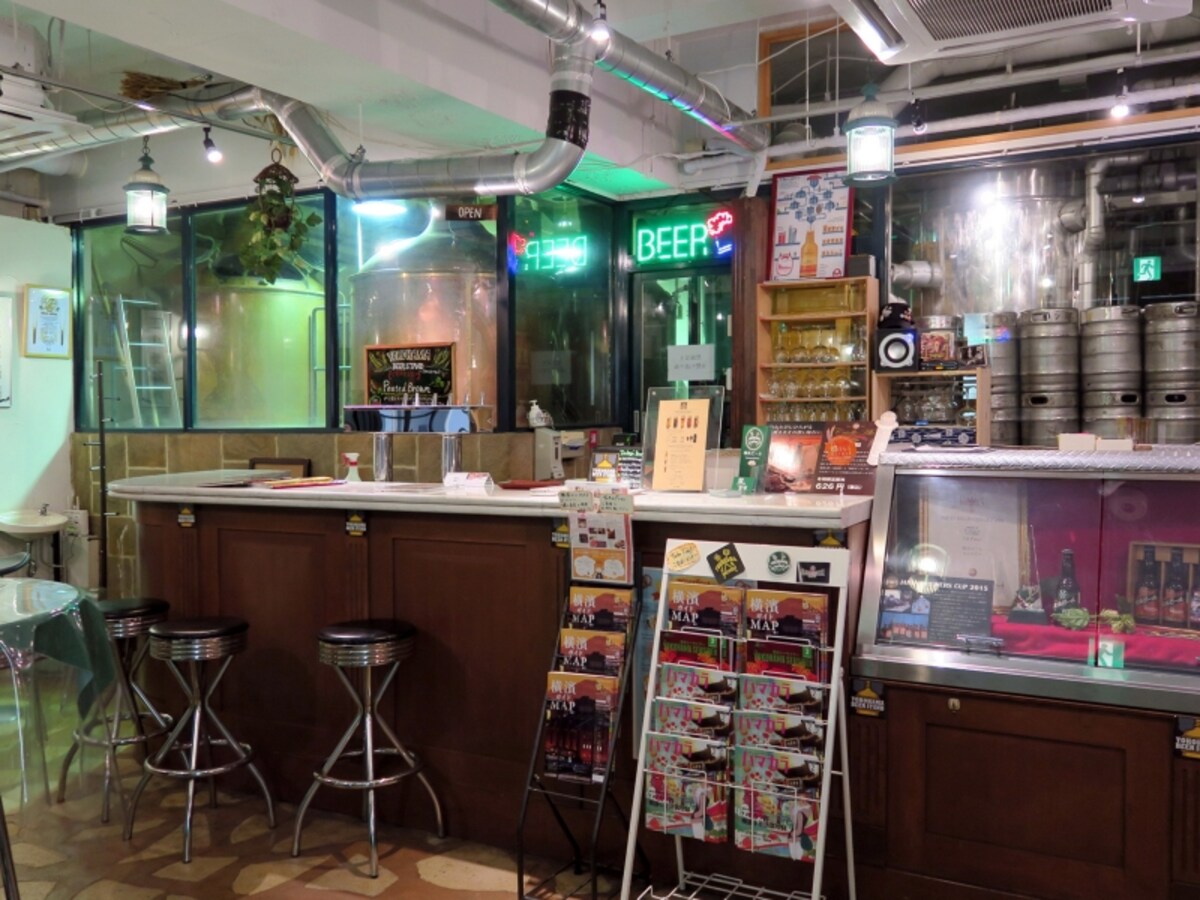 1階はビールタンクが並ぶ醸造所。ビアスタンドが併設されており、Sサイズ（120ml 350円）から気軽にビールが楽しめる。瓶ビールの販売も