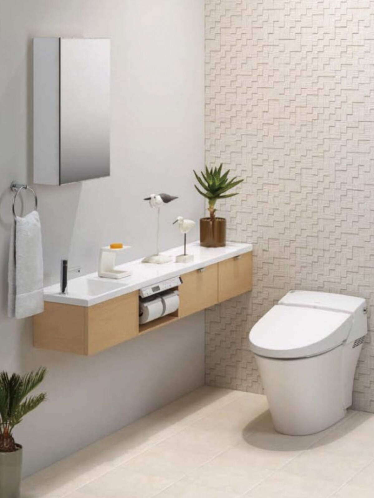 木目のあるキャビネットとホワイトのカウンター、素材感のある壁材を取り入れたトイレ空間。[キャパシア] 