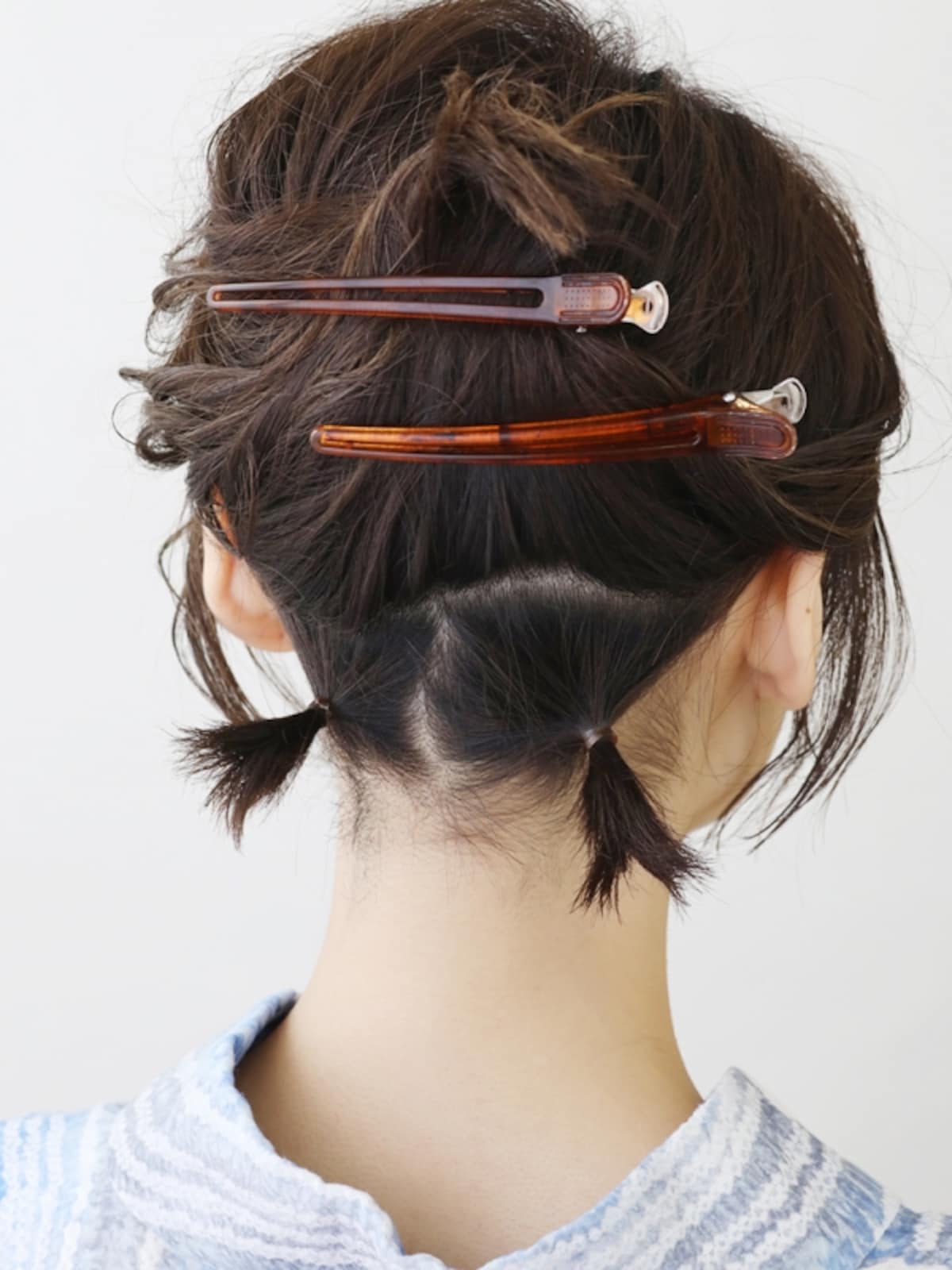髪色に近いヘアゴムで2か所結び、ショートヘア向け夜会巻きの土台を作る