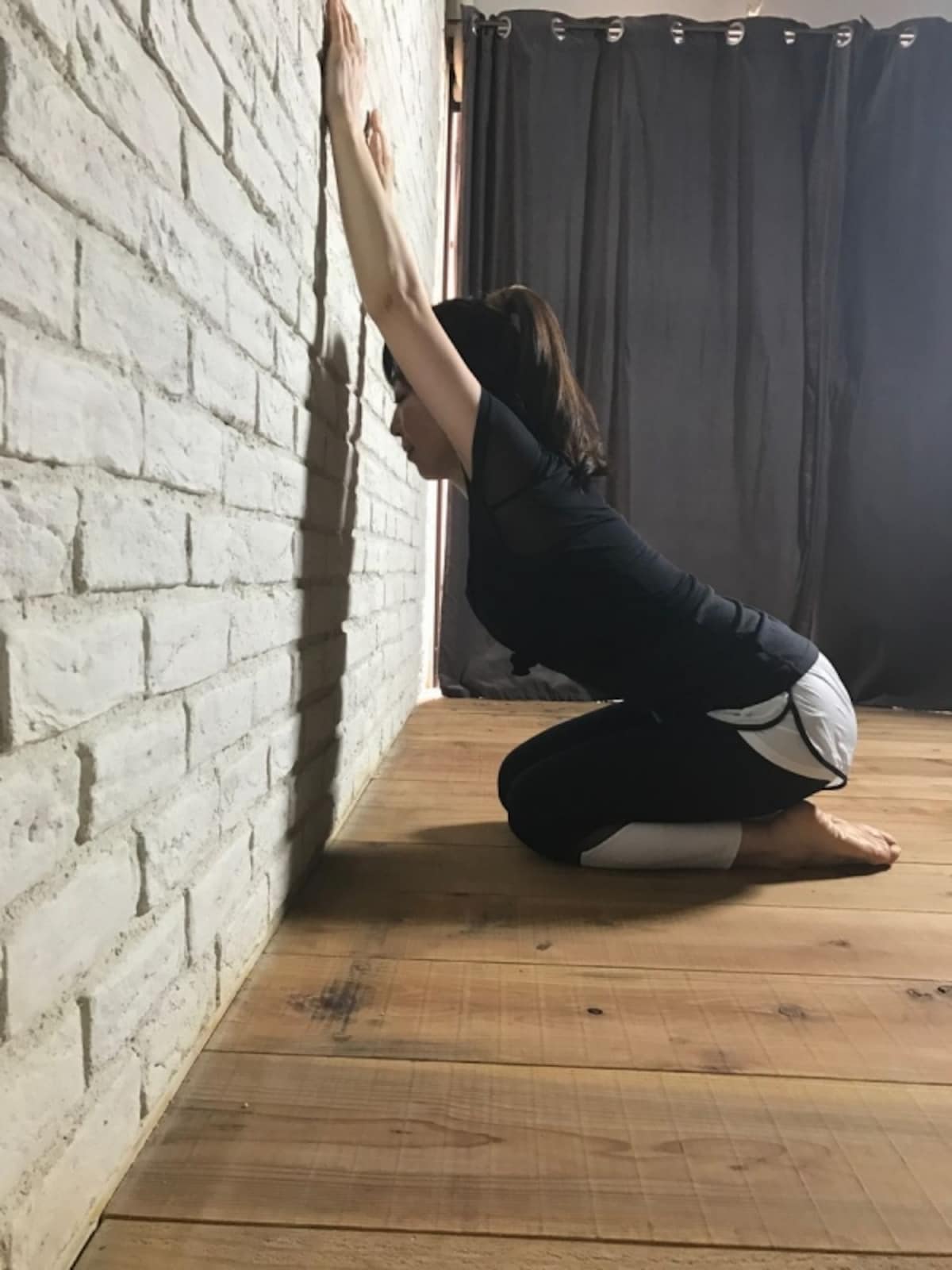 壁に体重をあずけるように