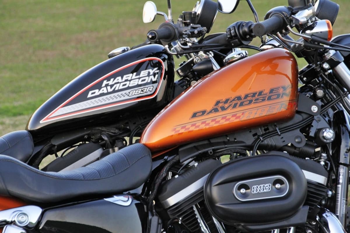 奥の黒いXL883Rは2008年式、手前のオレンジXL883Rが2015年式。2008～2010年モデルはバイクの頭脳となる「ECM」というコンピューターがシート下に設置されていてカスタムしづらい、というデメリットが潜んでいる