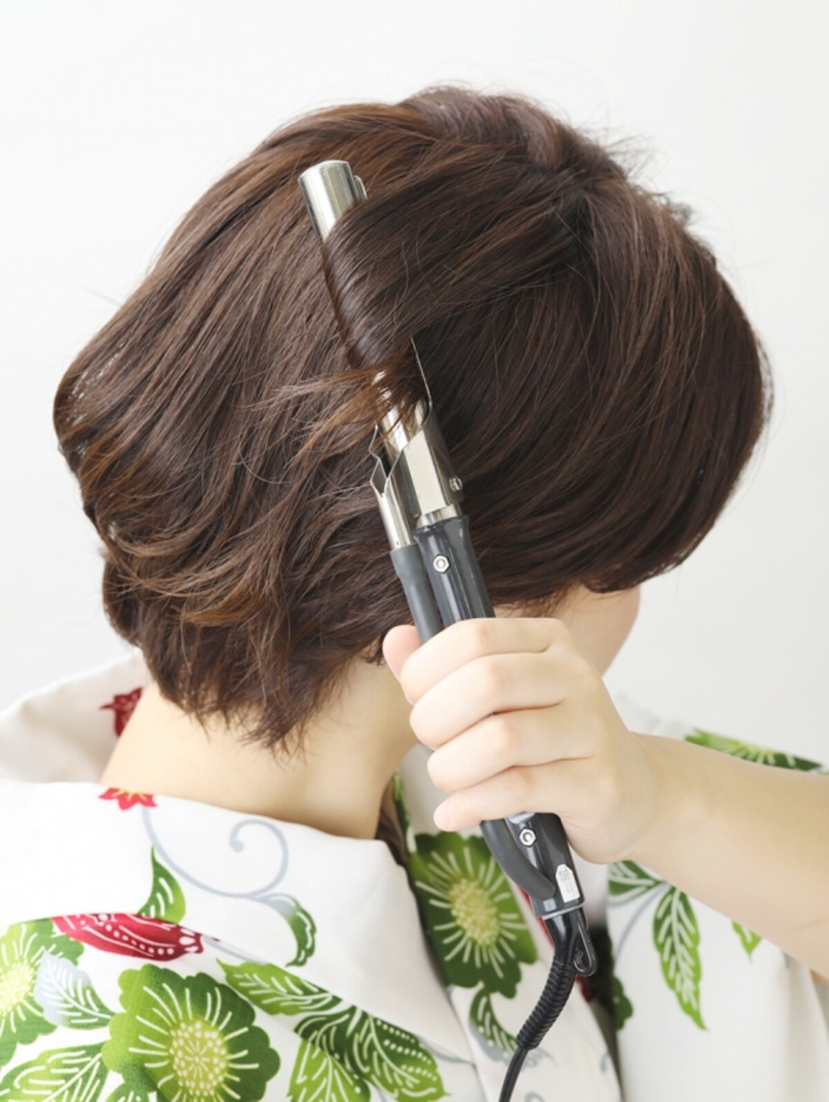 細めのコテで根元から髪を巻く