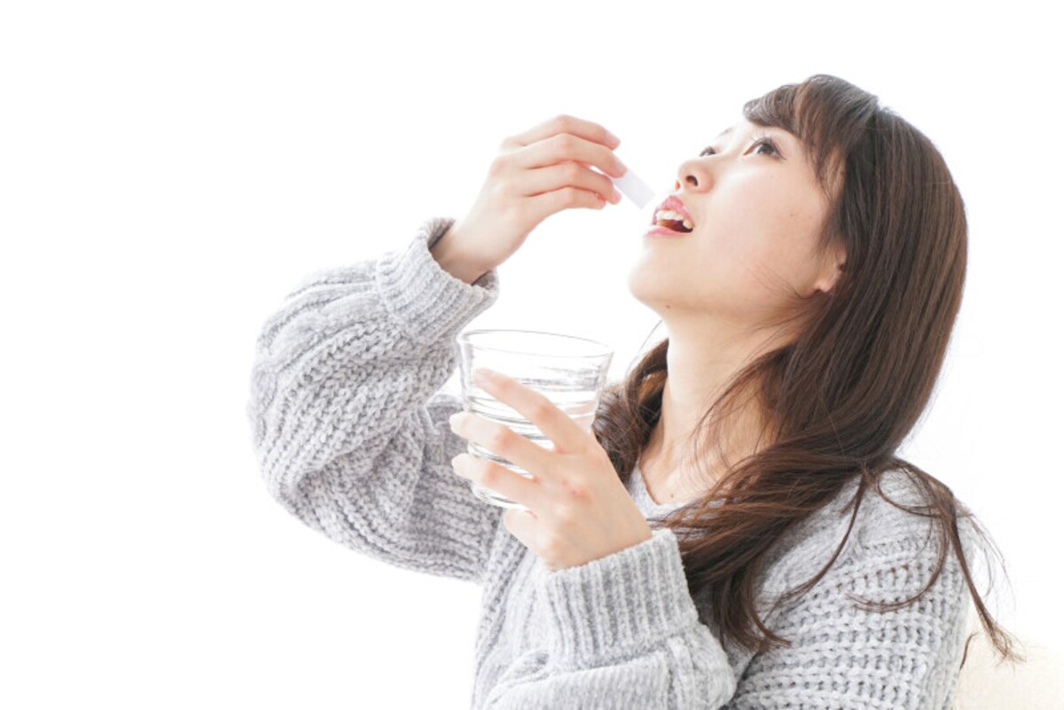 粉のサプリメントを飲む女性