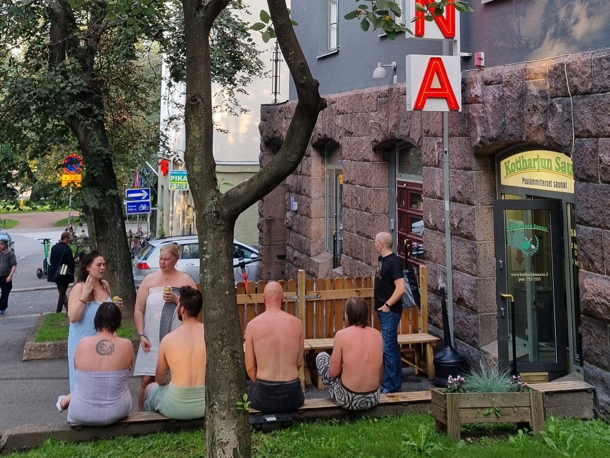 公衆サウナの店先で外気浴を楽しむ客。通行人も特に気に留めない