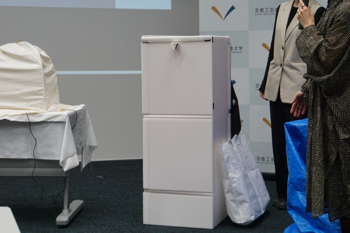 プラスチック段ボールにナノイーX発生器を入れて使う「組み立て消臭クローゼット」。「プラスチック段ボールでできており、たたむと45cm四方くらいで大きめのトートバッグに入るサイズになります。日常的な使い方としては、例えばレジャーで煙の匂いが付いたアウターを入れる、洗いにくいウールの衣類を毎晩かけておくといったことを想定しています」（畔柳助教）