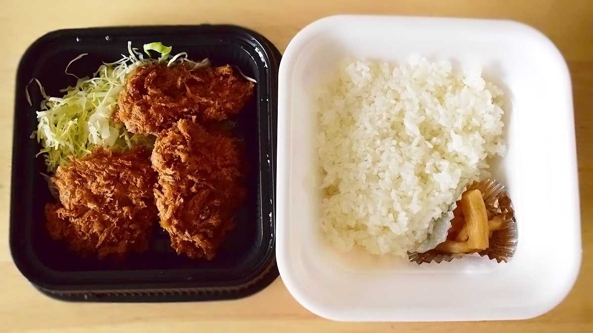 持ち帰り容器の上段にはヒレカツ3枚と千切りキャベツ、下段にはご飯が入っています。
