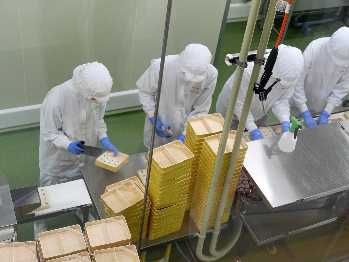 工場では、スタッフが左手に弁当箱を持ち、右側のスペースにごはんを詰めていた（筆者撮影）