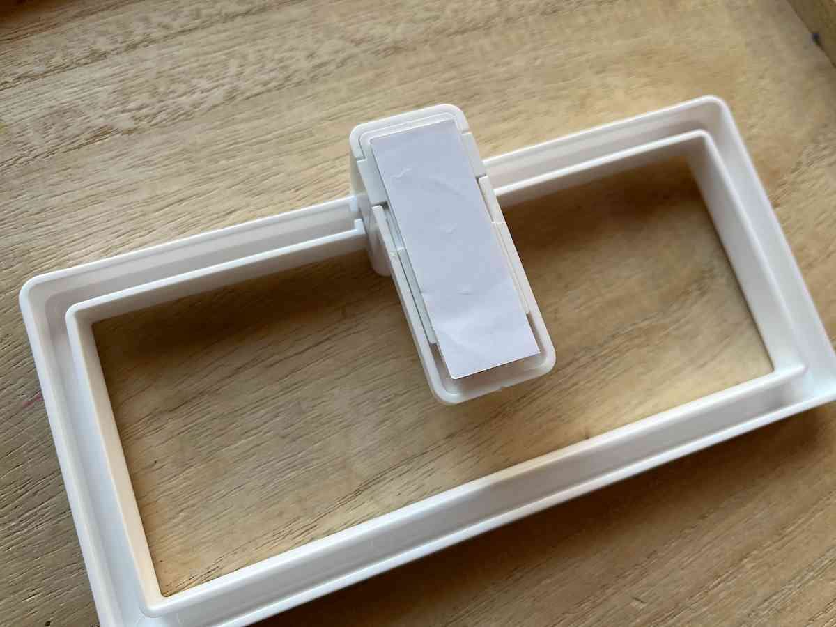 セリアの「はがし跡が残りにくいタオルハンガー」専用の粘着テープを本体裏面に貼る