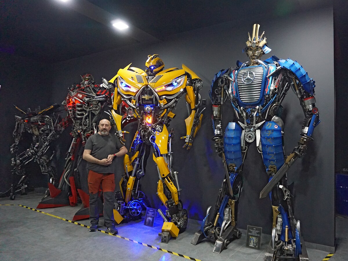 車の廃材などを使ったロボットを作るアーティスト、セバスチャン・クハルスキ氏。トランスフォーマーにインスパイアされた作品の前で