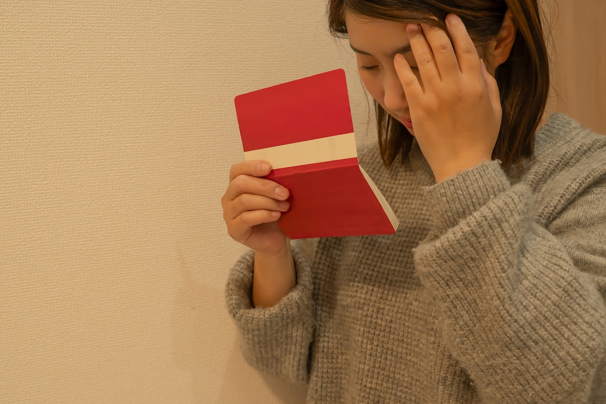 通帳を見て落ち込む女性