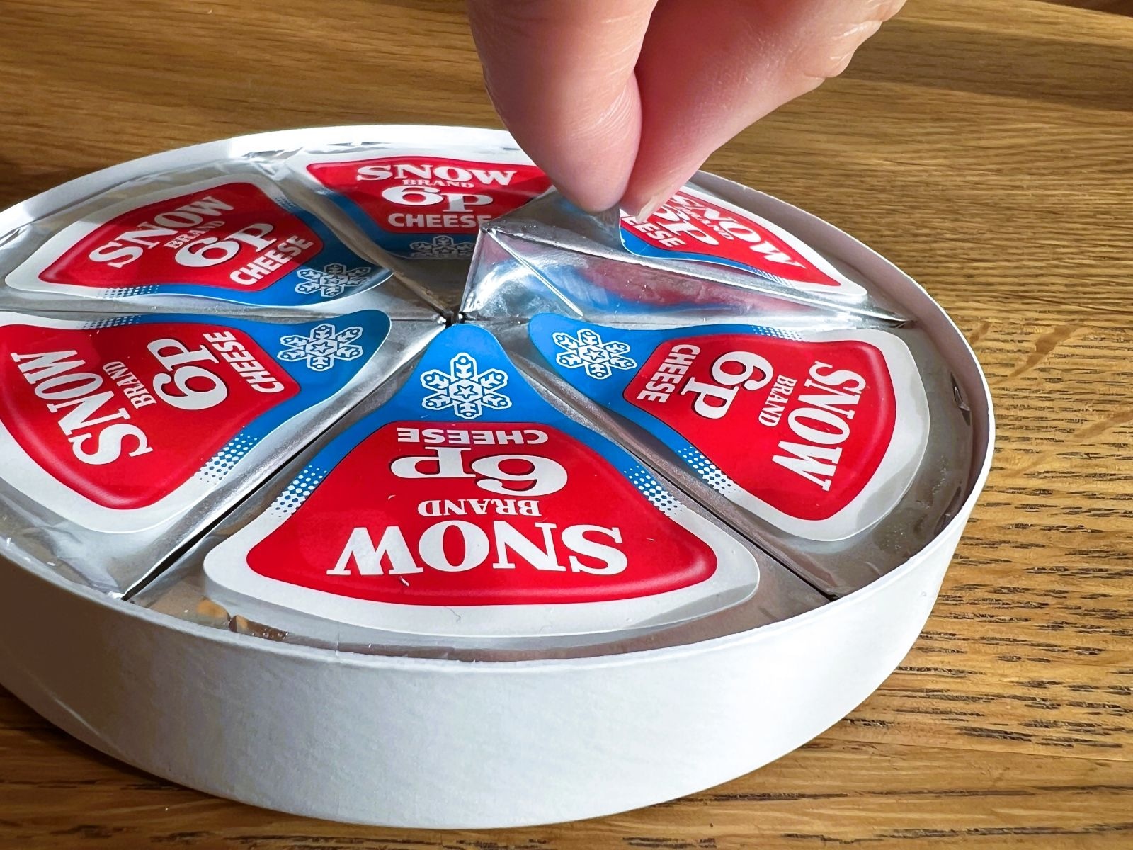 ６Pチーズの「ヒラヒラ」をつまむ様子（All About ニュース編集部撮影）