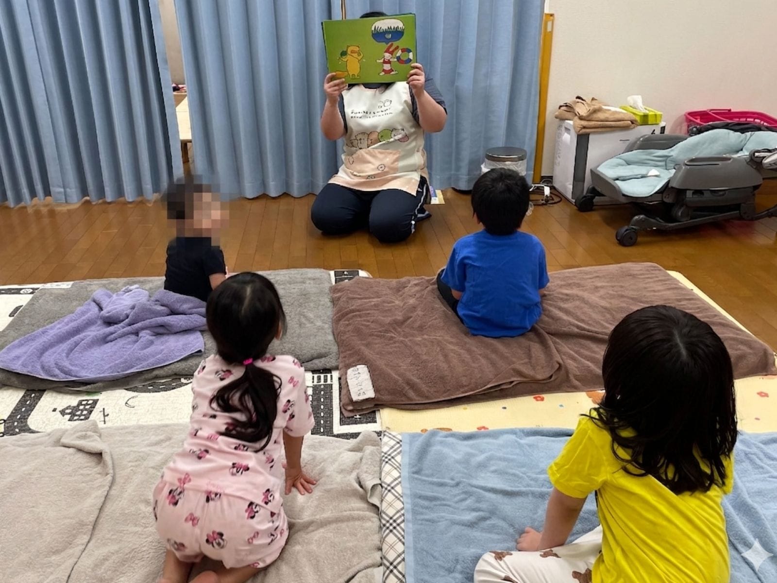 就寝前、保育士による絵本の読み聞かせを真剣に聞く子どもたち