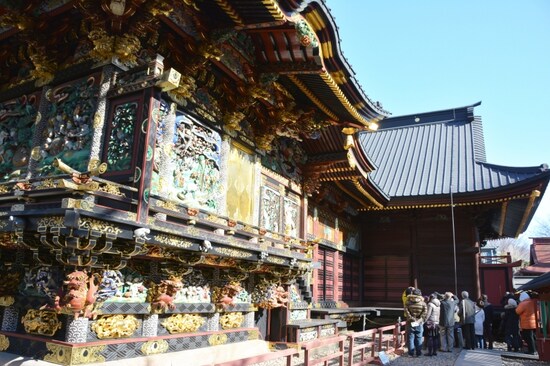 本殿左面の彫刻を解説する地元のボランティア・ガイド