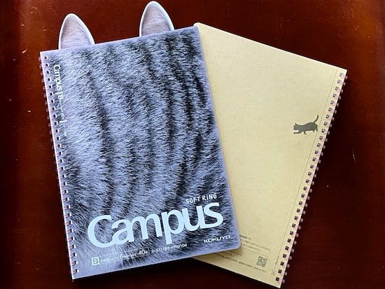 「限定 キャンパス肉球ソフトリング」の思い切ったデザインは、表紙だけでなく、裏表紙にもイラストの猫がいて、さらにバーコードにもしっぽが付いているなど、細部まで徹底している。オマケの猫耳ふせんをつけて写真を撮ってみた