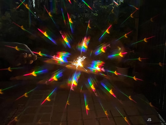 線香花火の小さい光を撮影。周辺に虹色の光が写った。