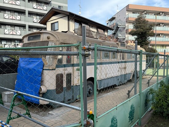 川崎市高津区の二子塚公園に保存されているトロリーバスの車両。車両を覆っていた屋根が撤去され、車両前面にはブルーシートがかけられていた（2024年12月18日撮影）