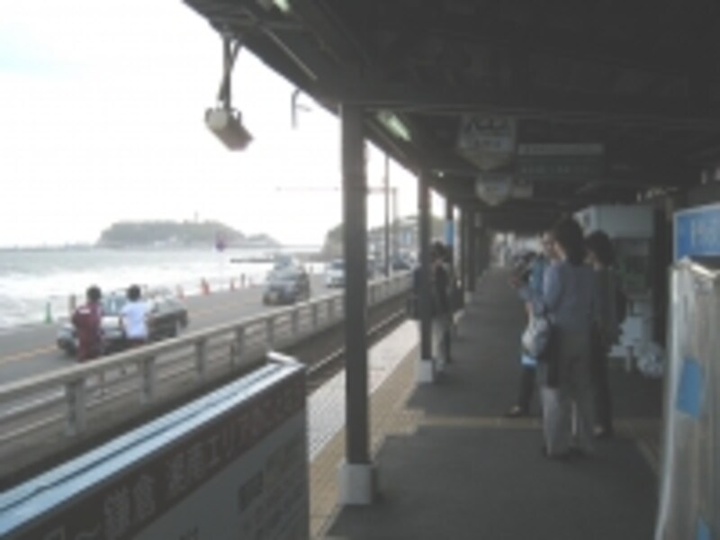 海に面した駅からは江ノ島（写真右手）が望める。駅舎と江ノ電、江ノ島を1枚に納めようとカメラ片手に待ち構える人も多かった