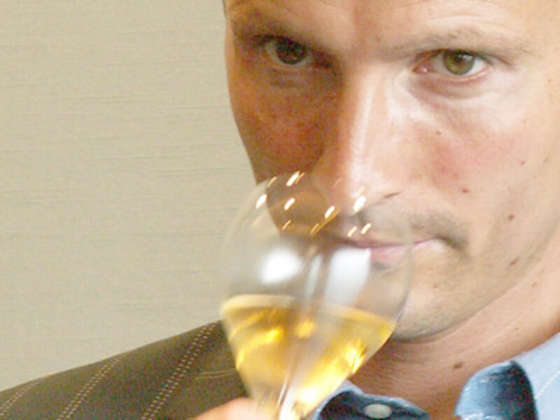 シャンパンの入ったグラスに鼻を近づけて香りを嗅ぐ男