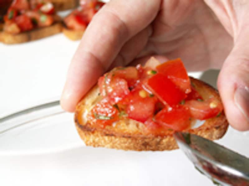 スプーンでトマトをバゲットのスライスにのせる