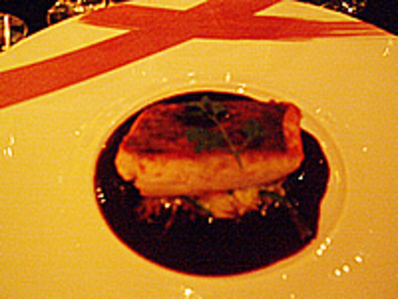 皿の中央部にグリルした魚の切り身とその下に濃い色のソース