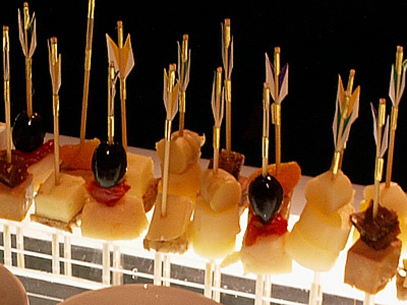 黒オリーブなどを矢羽根の飾りが付いた楊枝で串刺しにした小さなオードブル