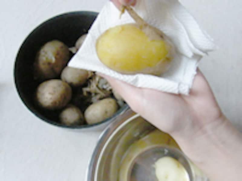 ジャガイモを手のひらのキッチンタオルに乗せて皮をむいています