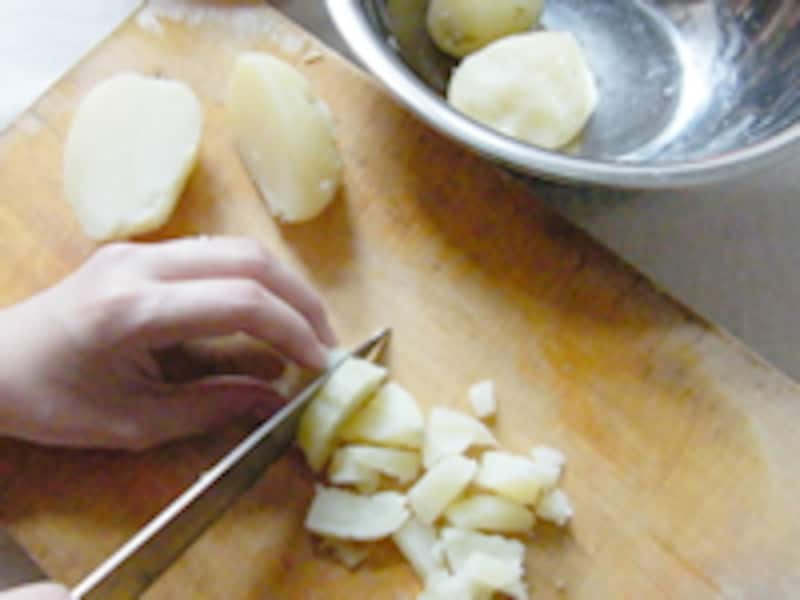 皮をむいたジャガイモをサイコロ状に切っています