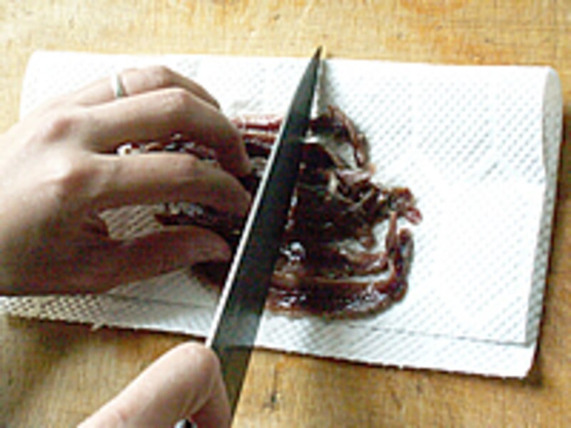 まな板の上のキッチンタオルに乗せたアンチョビを切っているようす