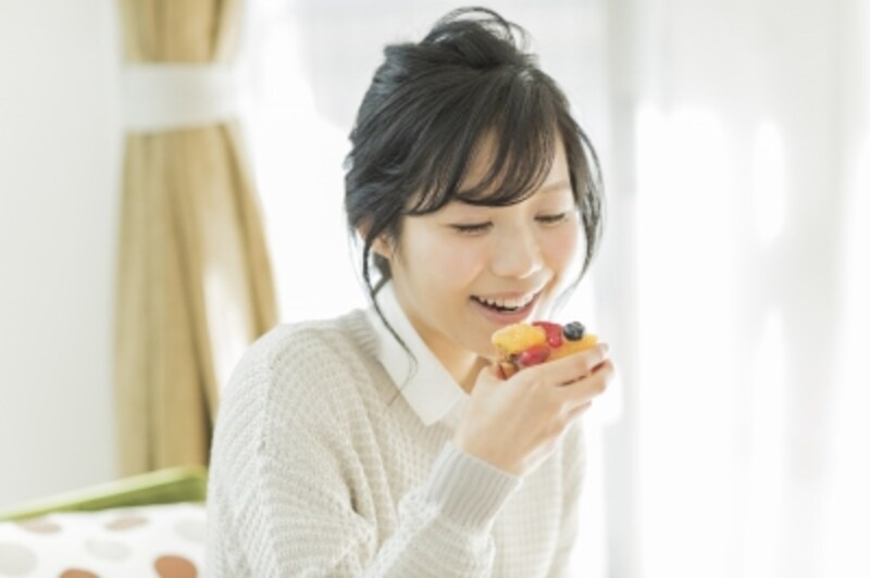 味わう時や美味しいものを口にした時に目をつぶる女性/咀嚼している最中に手で口を覆う女性