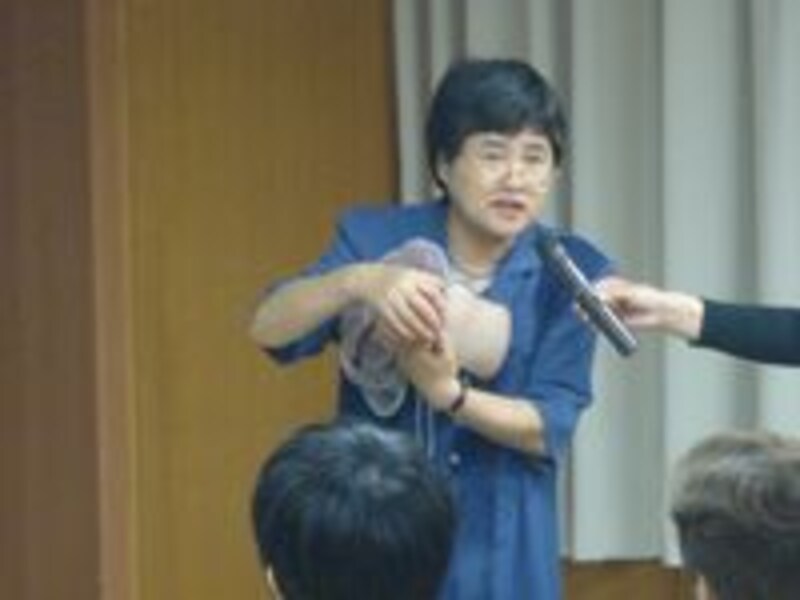 赤ちゃんの人形を持って説明する助産師の岡本喜代子先生