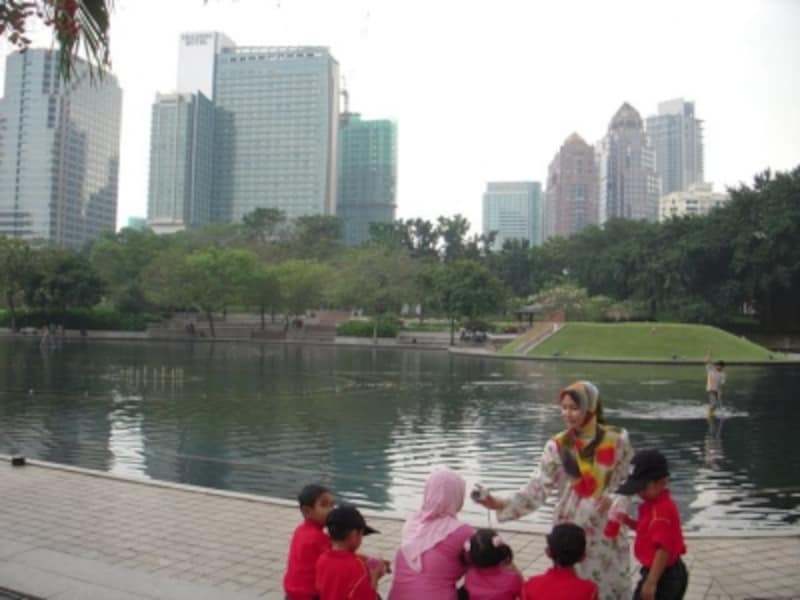 公園でくつろぐマレー系の女性と、子供たち