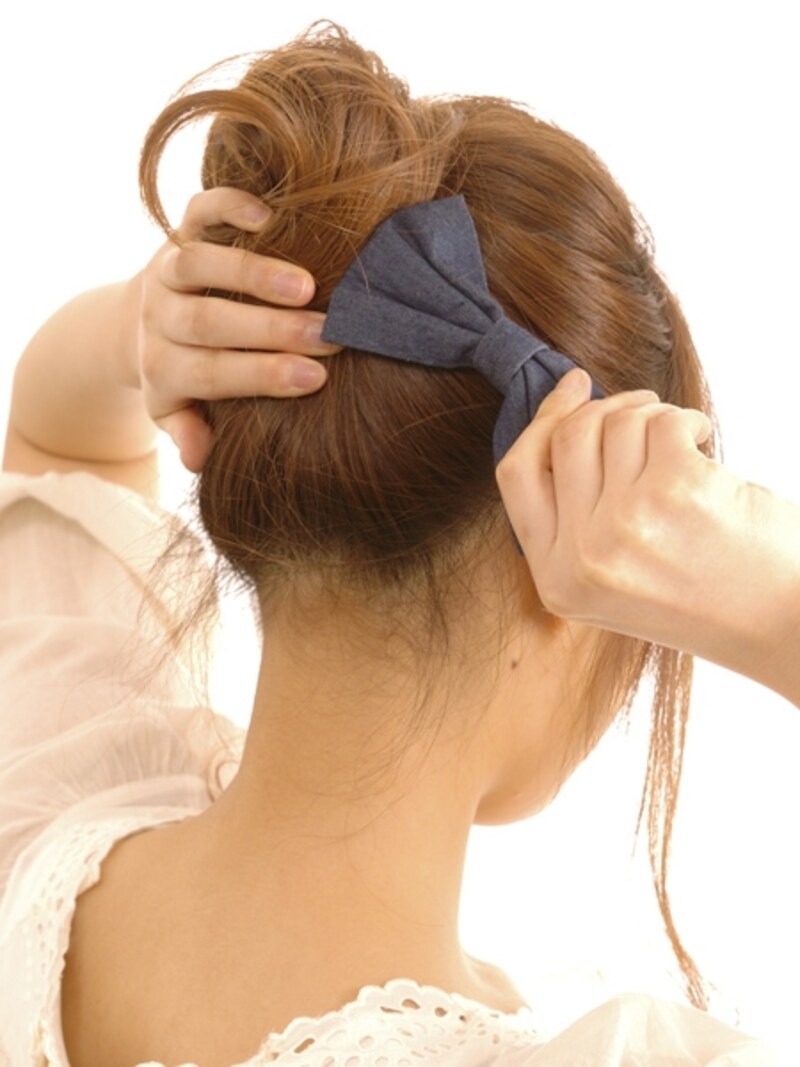 ねじり上げた毛束がたるまないよう、片手で押えながらクリップを