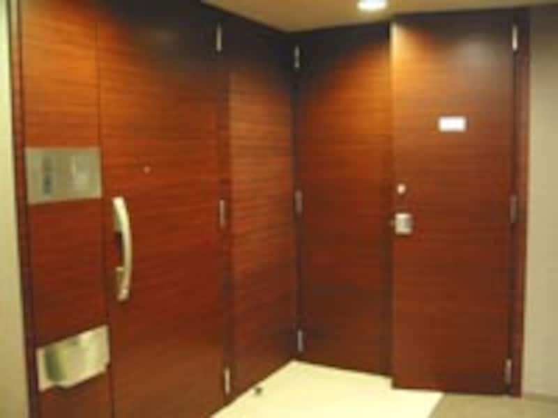 重厚なイメージの玄関ドア(最上階メゾネットプラン)。全住戸の玄関はアルコーブやポーチでプライバシーが保たれるようになっている。また、各住戸にトランクルーム(写真奥)も設置される