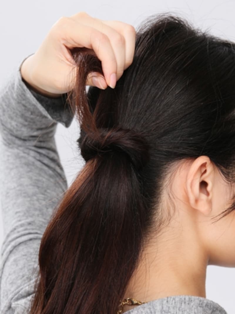 4. ゴムの結び目にねじった毛束を巻きつけていく。