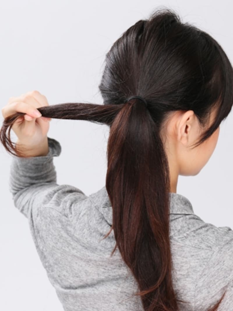 2．ゴムの結び目の下側の毛束を分け取る。