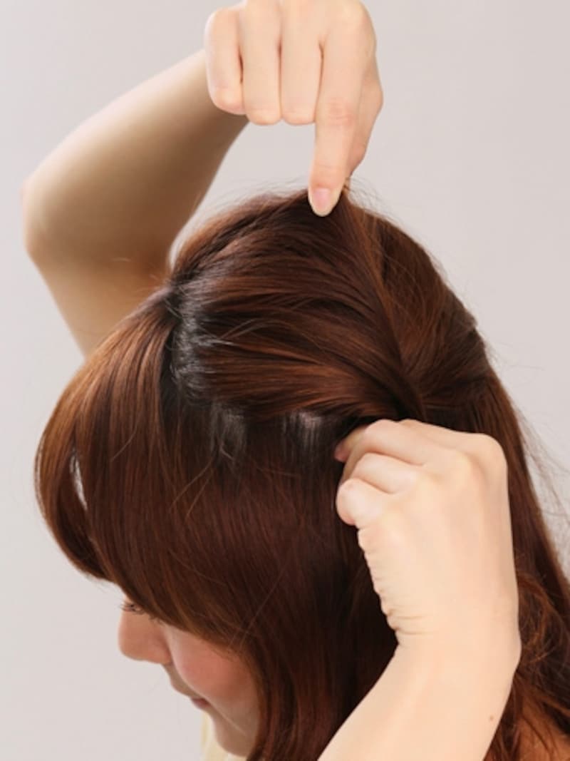 3ねじった髪を押さえながら、トップの髪を引き出してボリュームアップ。