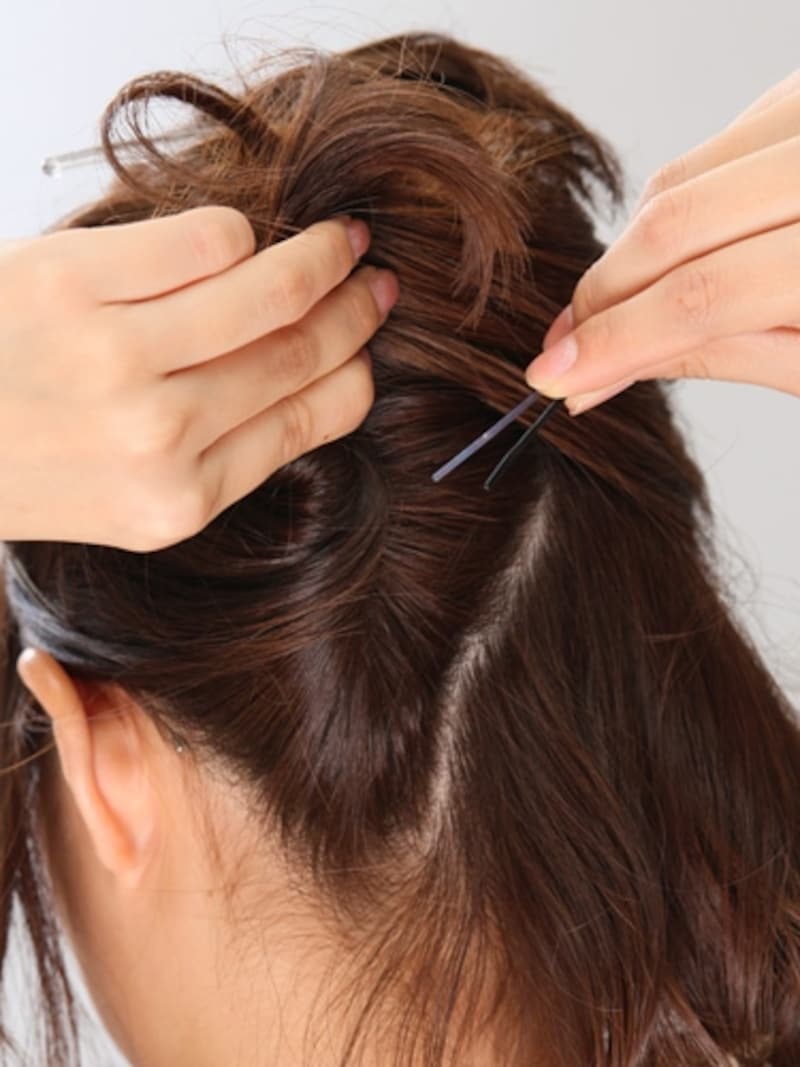 2襟足の髪をやや斜めに左右で分けて、左側の髪から上に向かってねじる。