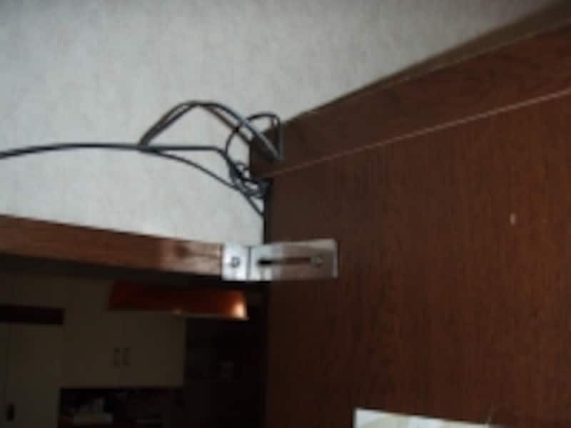 L型金具の使用例。食器棚の側面と建具枠とを金物で固定※1。