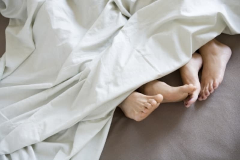 ベッドに寝ているカップルの足