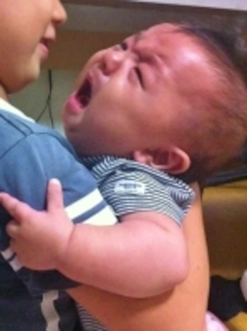 大泣きして抱っこされる赤ちゃんの写真
