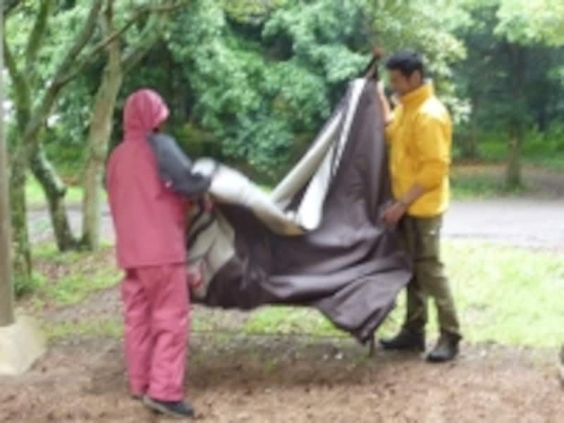 雨の中でテントをたたんでいる